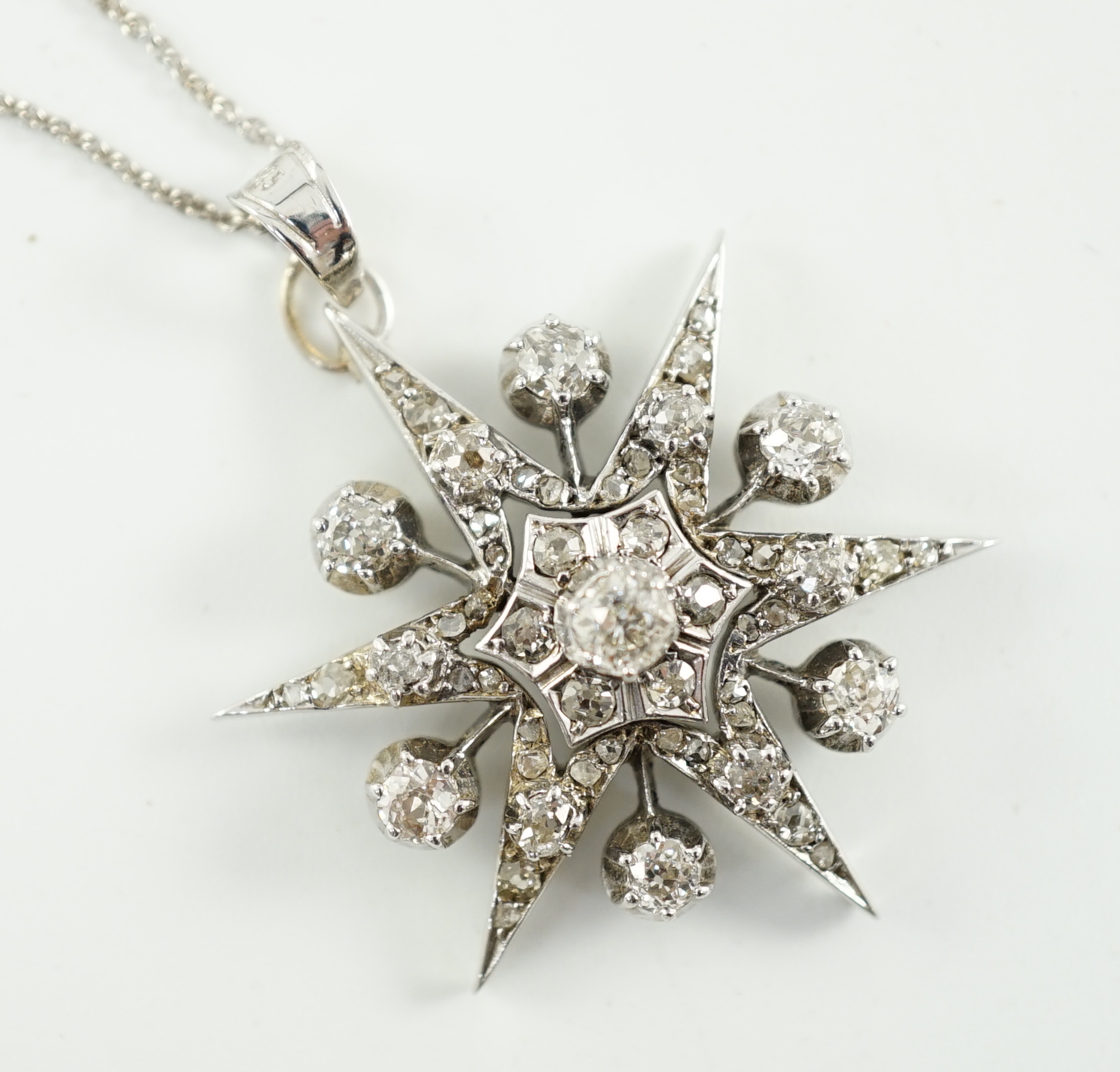 A Victorian white gold and diamond cluster set star burst pendant, on a later sterling chain